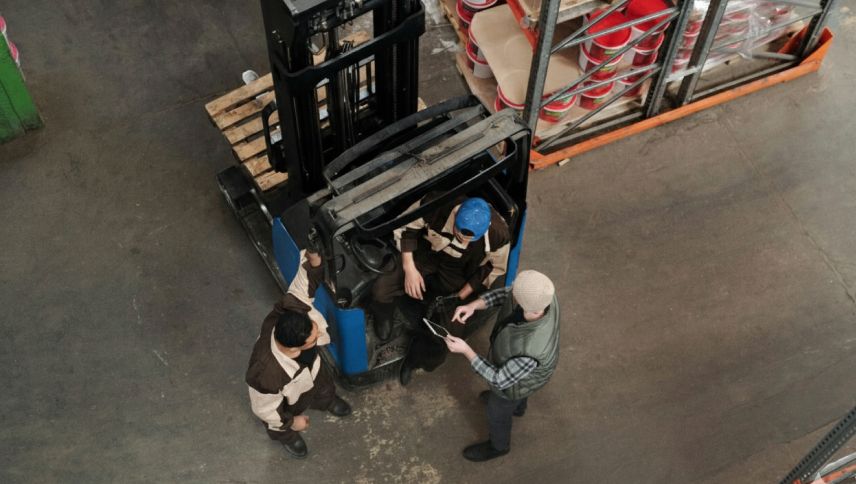 pracownicy stojacy przy wozku widlowym