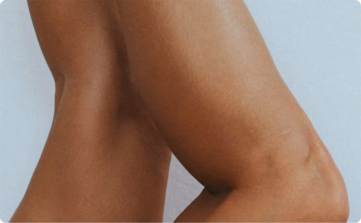 Vue rapprochée de jambes croisées, peau lisse sur fond bleu clair