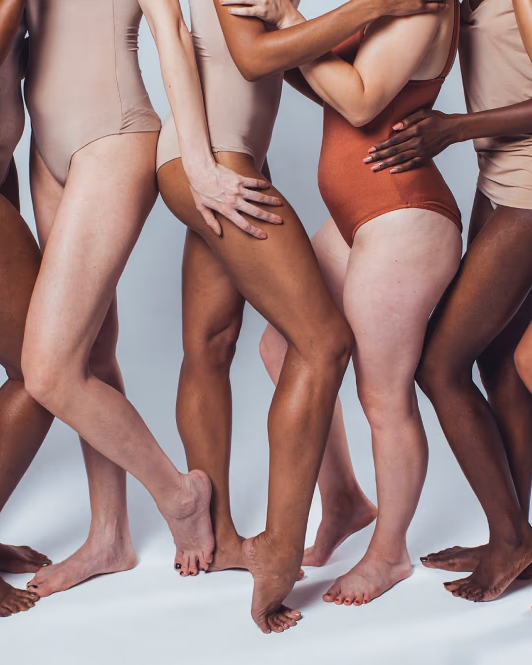 Groupe de jambes de femmes de différentes carnations, debout côte à côte, en tenue neutre