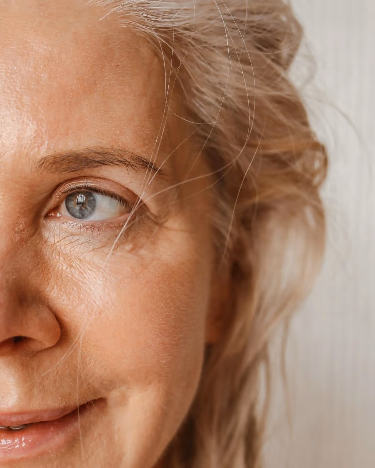 Portrait partiel d’une femme mature au regard apaisé, cheveux gris et peau lumineuse