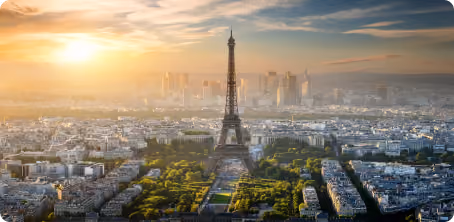 Aerial view of the Eiffel Tower with Paris cityscape and sunset sky in the background.