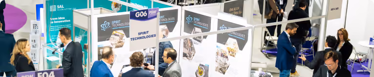 People networking and viewing booths at a technology trade show with Spirit Technologies signs.
