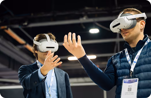 Two men wearing VR headsets and reaching out with their hands to interact in a virtual space.