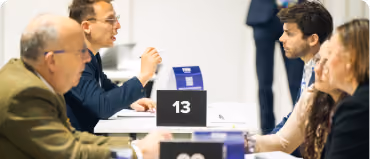 People engaging in conversation across tables with number signs in a professional setting.