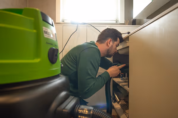 Bert gebruikt zuiger om ontstopping te verhelpen in afvoerleiding