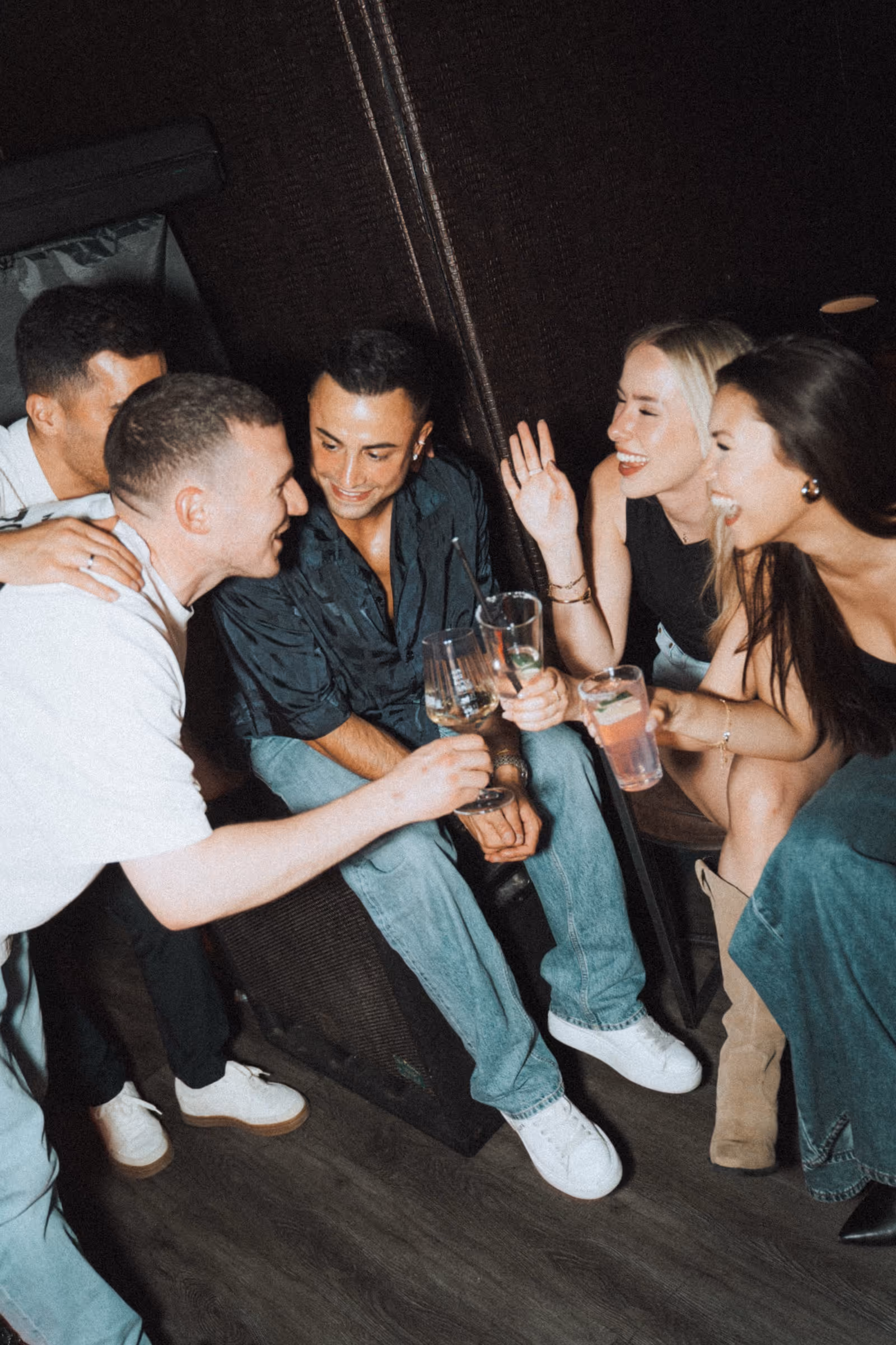 Personengruppe sitzt im Kreis und hat Spaß. Alle halten in ihren Händen Getränke.