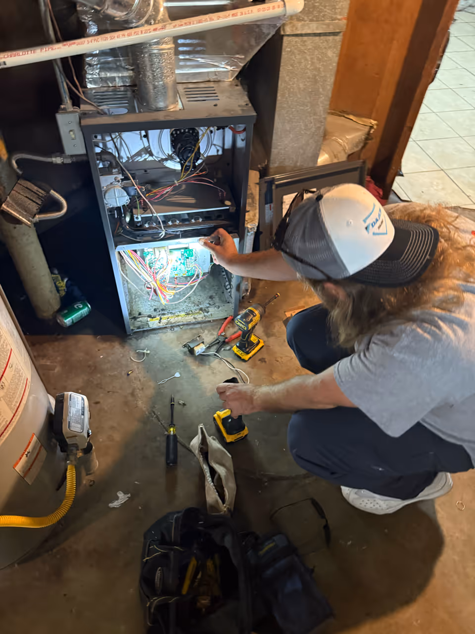 A technician inspects the wiring inside a furnace during routine maintenance.
