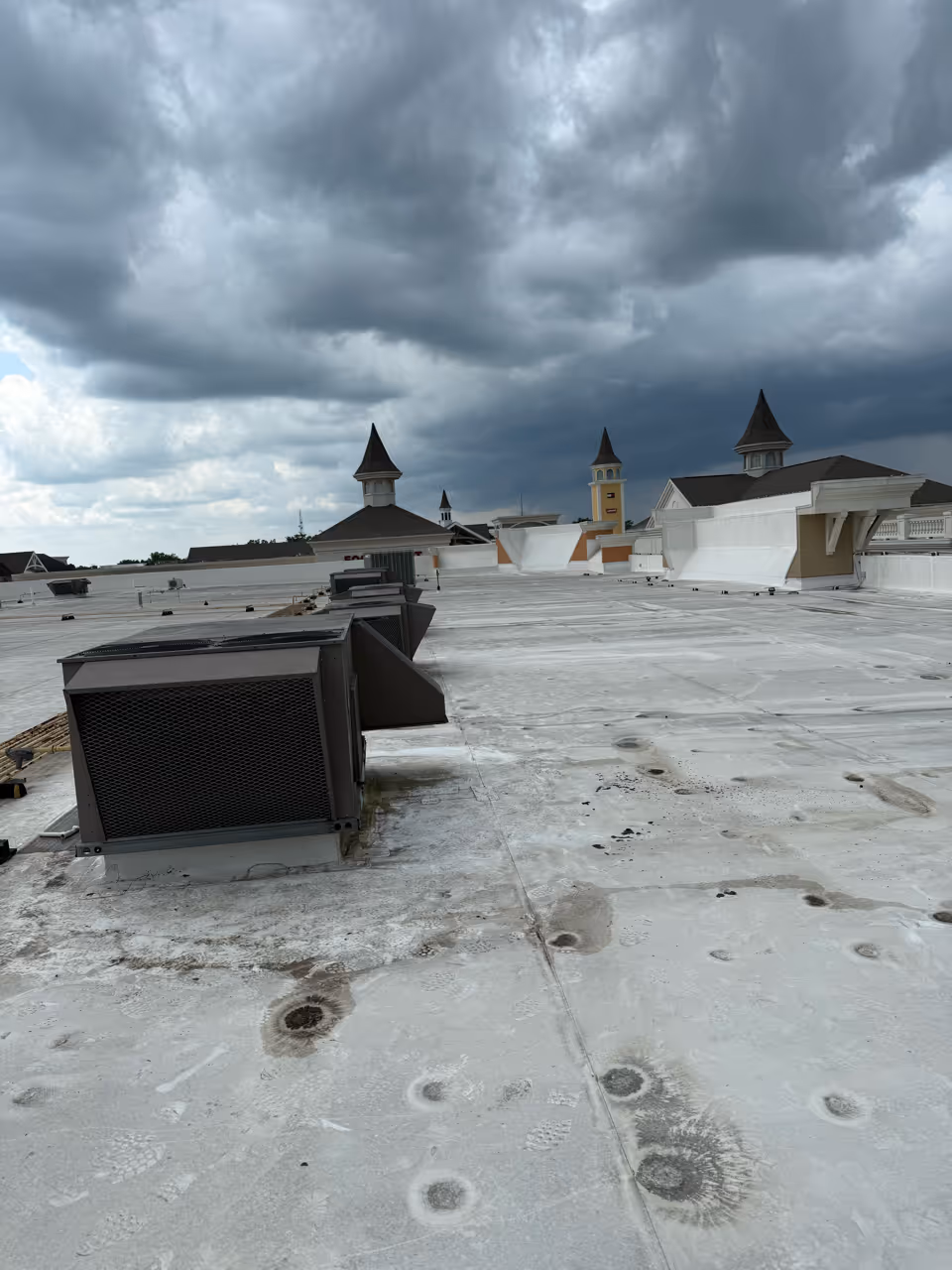 Cloudy sky over a rooftop with HVAC units and decorative tower structures.
