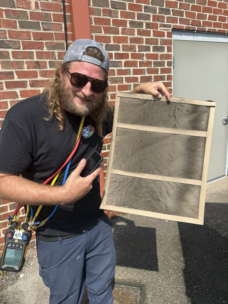 A technician wearing a hard hat and overalls, holding a clipboard.