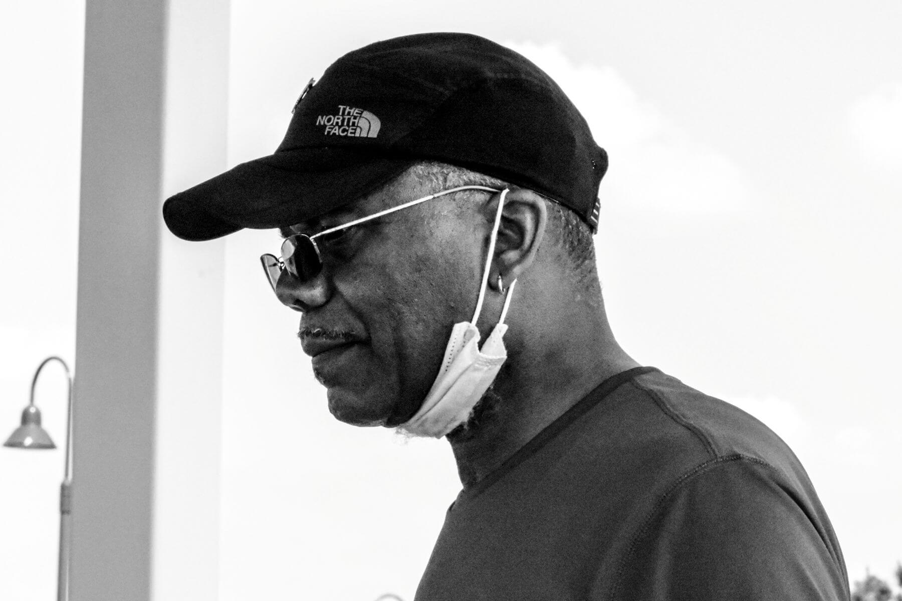 Older man in glasses and black North Face hat. Black and white.