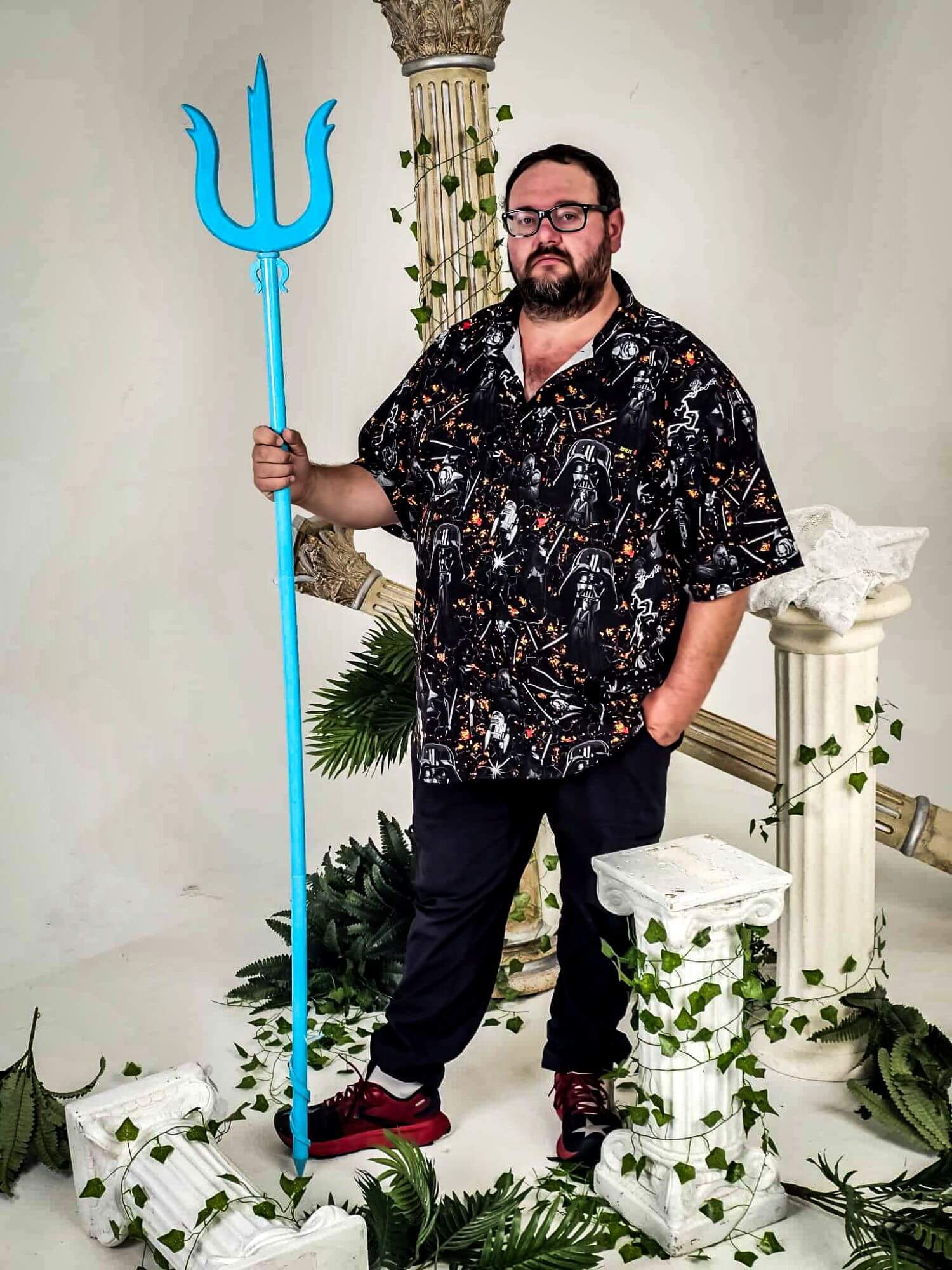 Jon Mishou standing on set with Greek pillars and blue trident.
