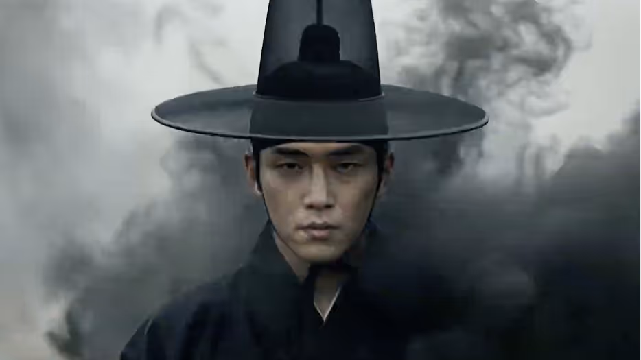 A man wearing traditional Korean black hat and clothing surrounded by swirling dark smoke with a serious expression.