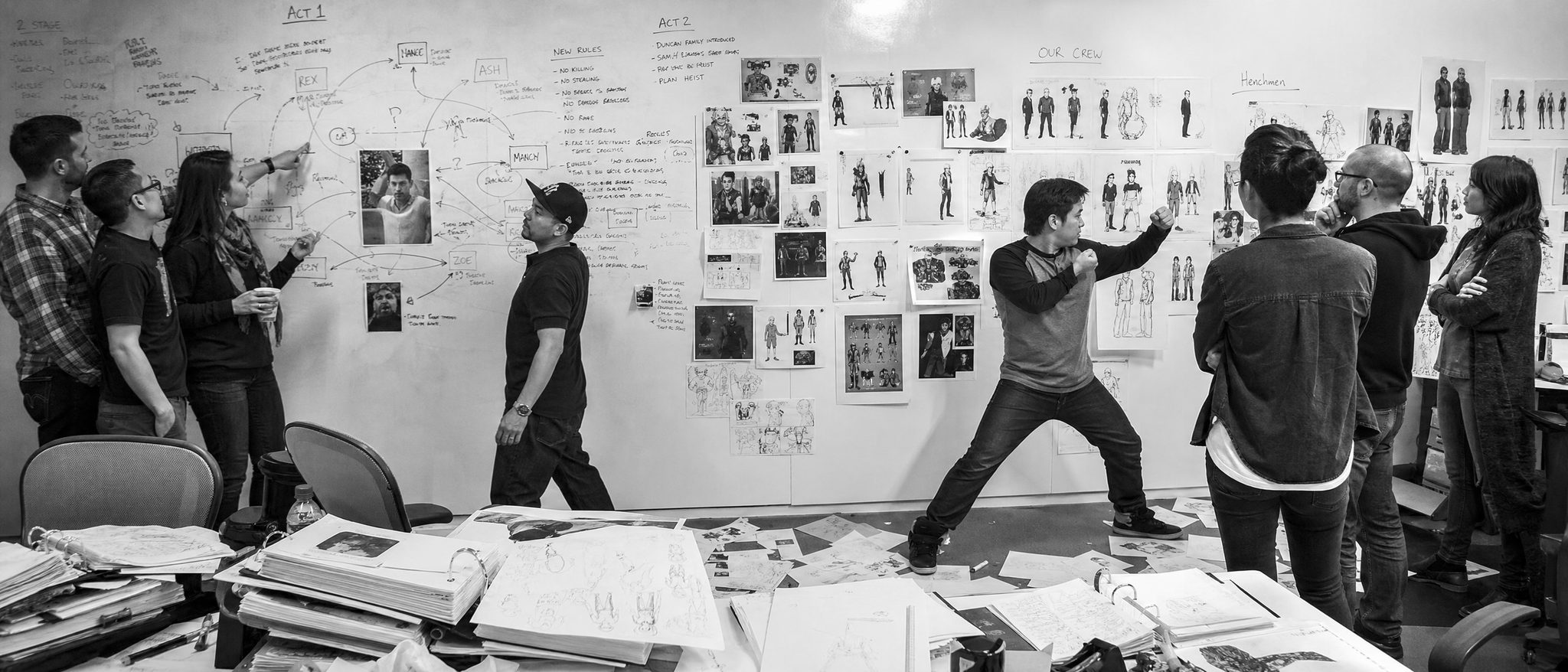 A story team pinning character sketches and notes to a whiteboard wall
