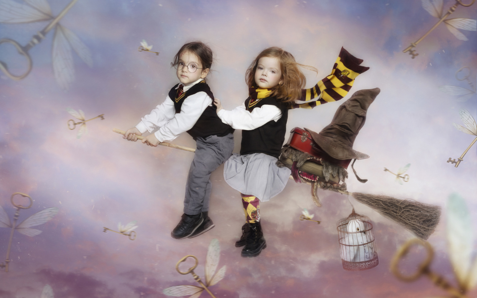 Bambini in uniforme di Hogwarts volano su scopa tra chiavi volanti e creature magiche in servizio fotografico ispirato a Harry Potter.