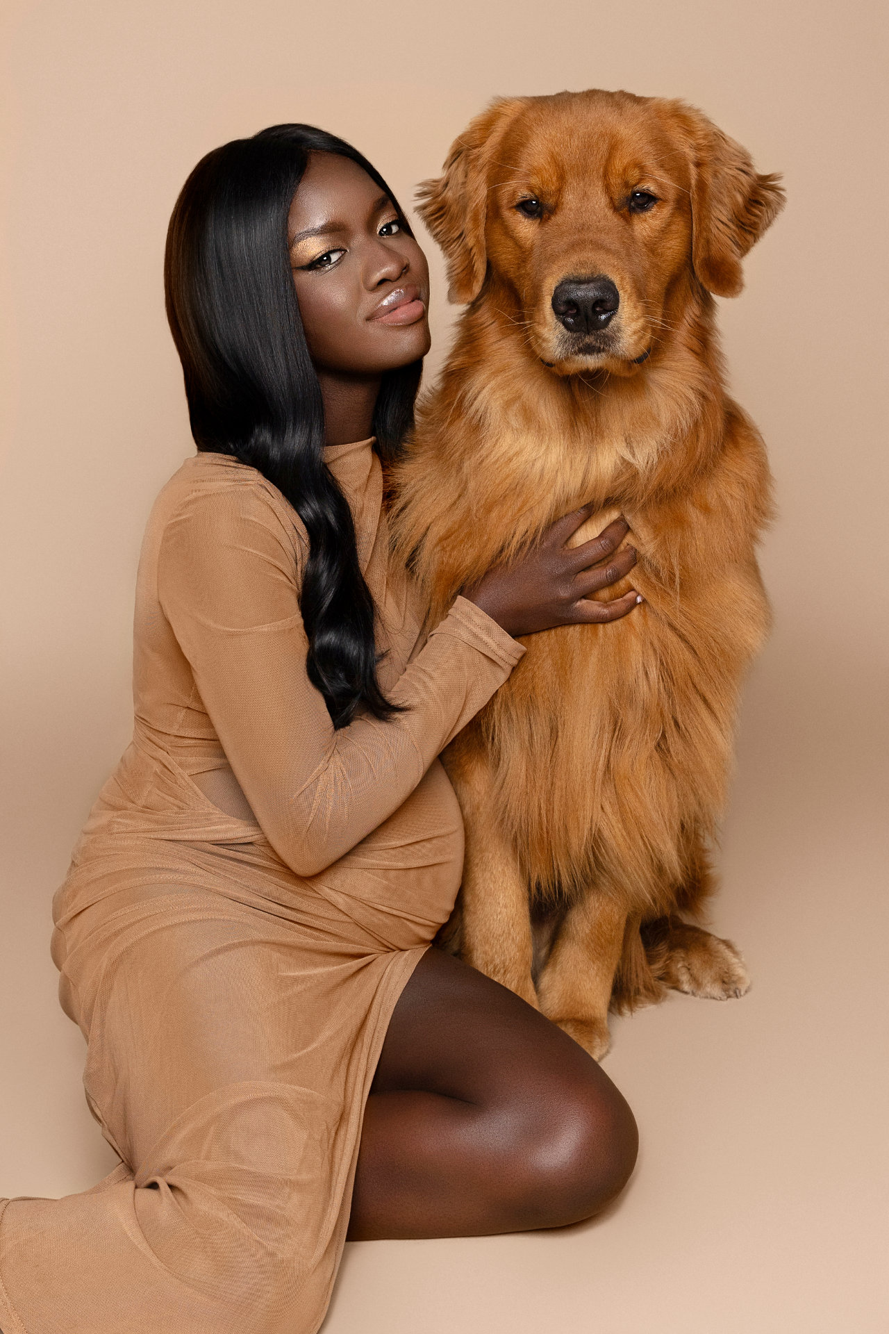 Ritratto affettuoso di maternità a Bologna con Claudia Spaziani: donna incinta e golden retriever su sfondo beige, armonia e calore.