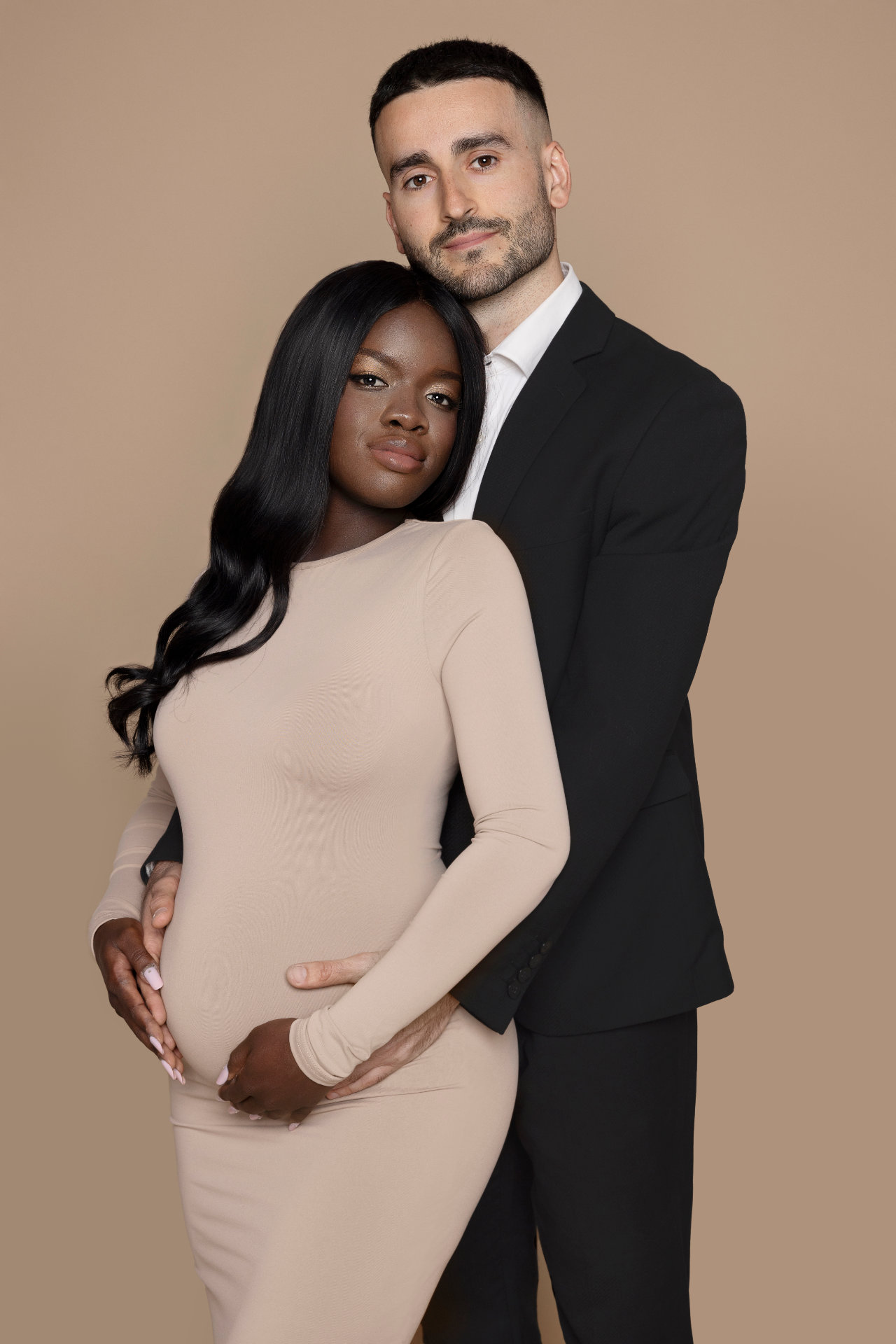 Servizio fotografico maternità a Bologna con Claudia Spaziani: coppia in abbraccio su sfondo neutro, stile sobrio e emozionale.