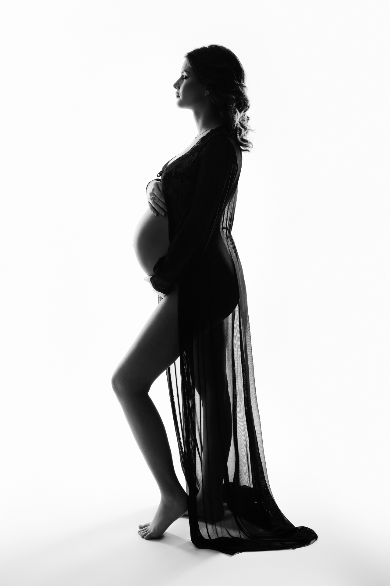 Ritratto di maternità in bianco e nero a Bologna realizzato da Claudia Spaziani: donna incinta in profilo con velo nero trasparente, posa elegante e luce drammatica.