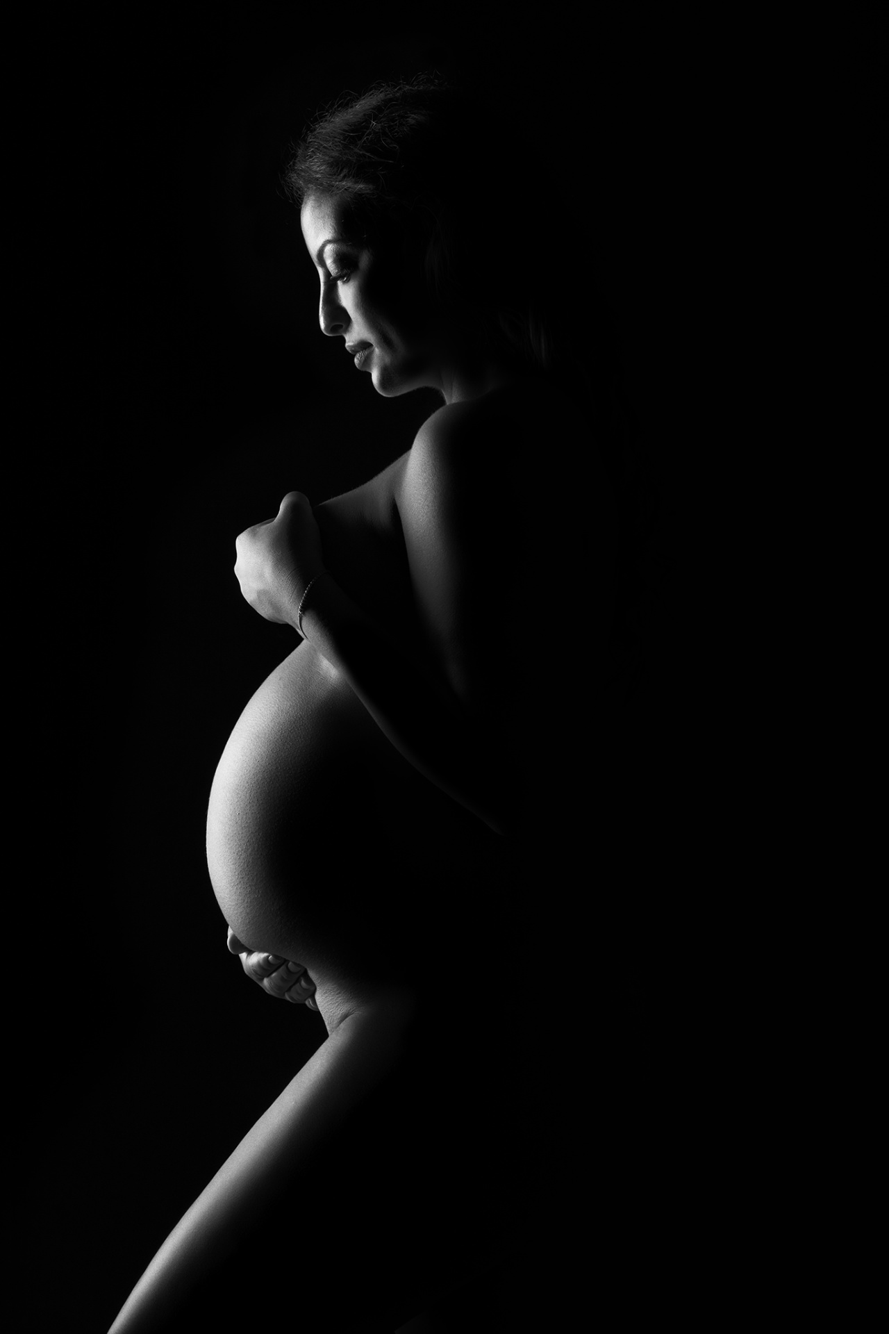 	Foto maternità a Bologna con Claudia Spaziani: donna incinta avvolta in tessuto trasparente, posa intima e luce soffusa.