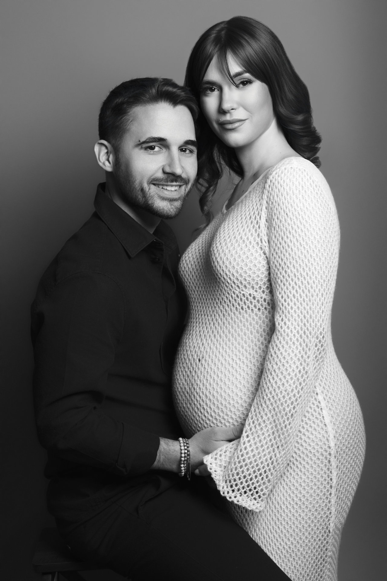 Ritratto di coppia maternità in bianco e nero a Bologna firmato Claudia Spaziani: donna incinta in abito bianco e partner in nero, posa elegante e intima.