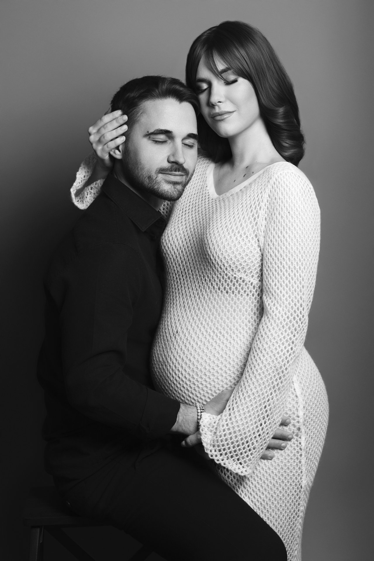 Foto artistica di coppia maternità in bianco e nero a Bologna con Claudia Spaziani: donna incinta in abito chiaro e partner che abbraccia, atmosfera intima e serena.