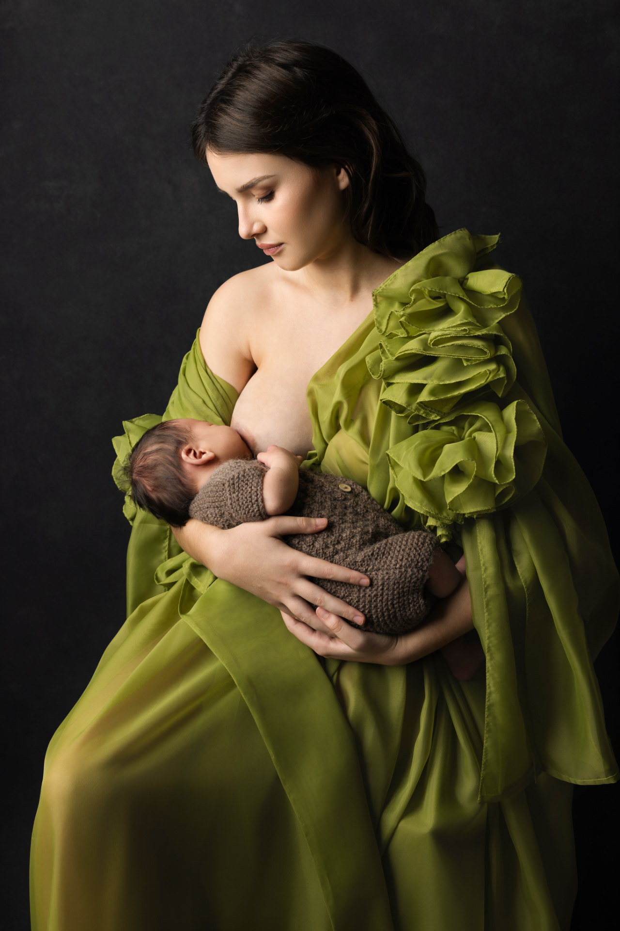 Fotografia newborn a Bologna di Claudia Spaziani: momento intimo di allattamento, mamma in abito verde con fiori e neonato in braccio.