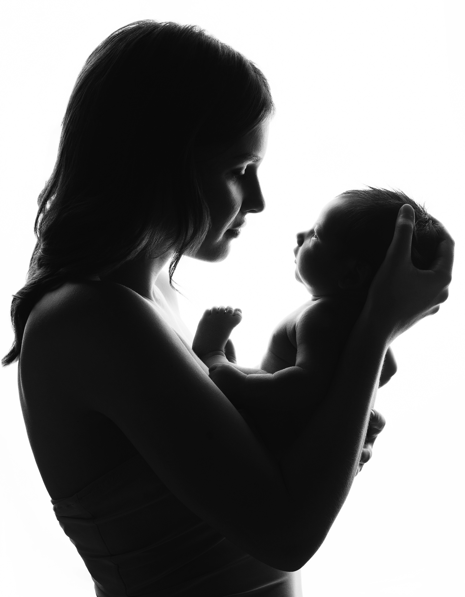 Servizio newborn a Bologna di Claudia Spaziani: silhouette in bianco e nero di adulto che culla il neonato con dolcezza.