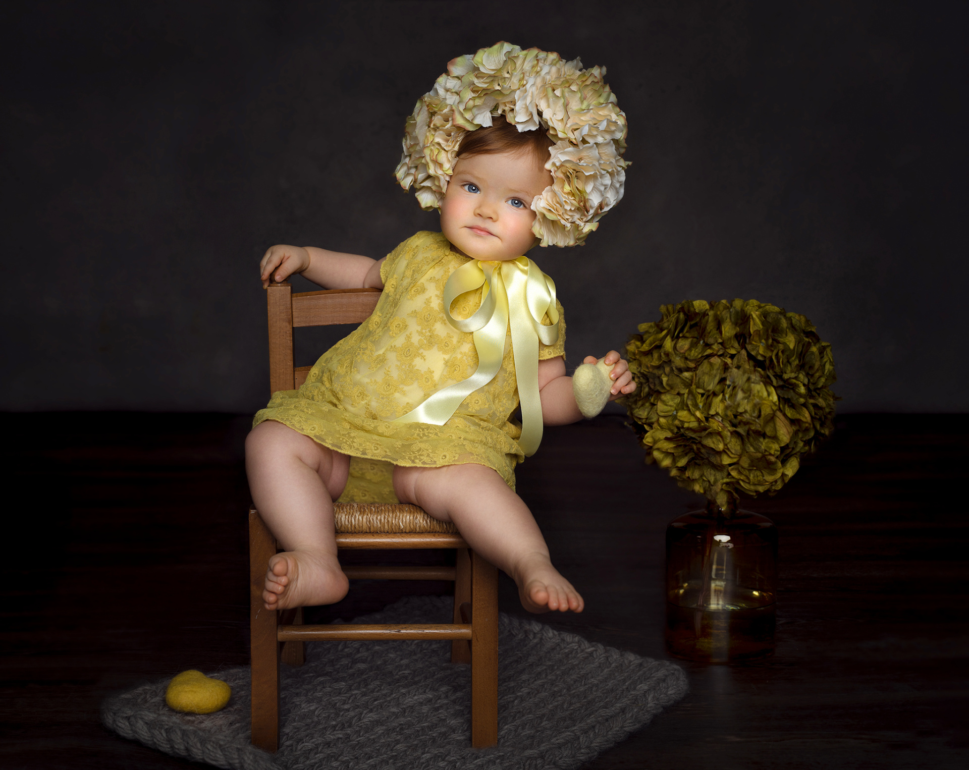 Ritratto in studio di bambina in abito giallo con fiocco e copricapo floreale, accanto a vaso di ortensie, realizzato da Claudia Spaziani a Bologna.