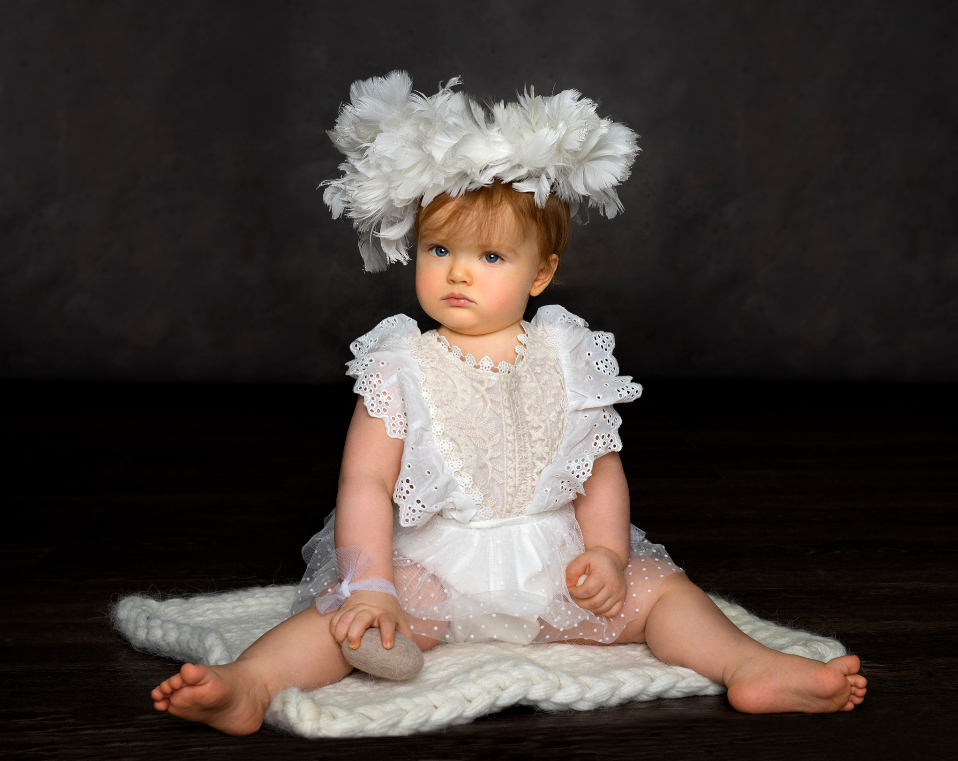 Ritratto elegante di bambina in abito bianco con piume e sfondo scuro, scattato da Claudia Spaziani nel suo studio fotografico a Bologna.