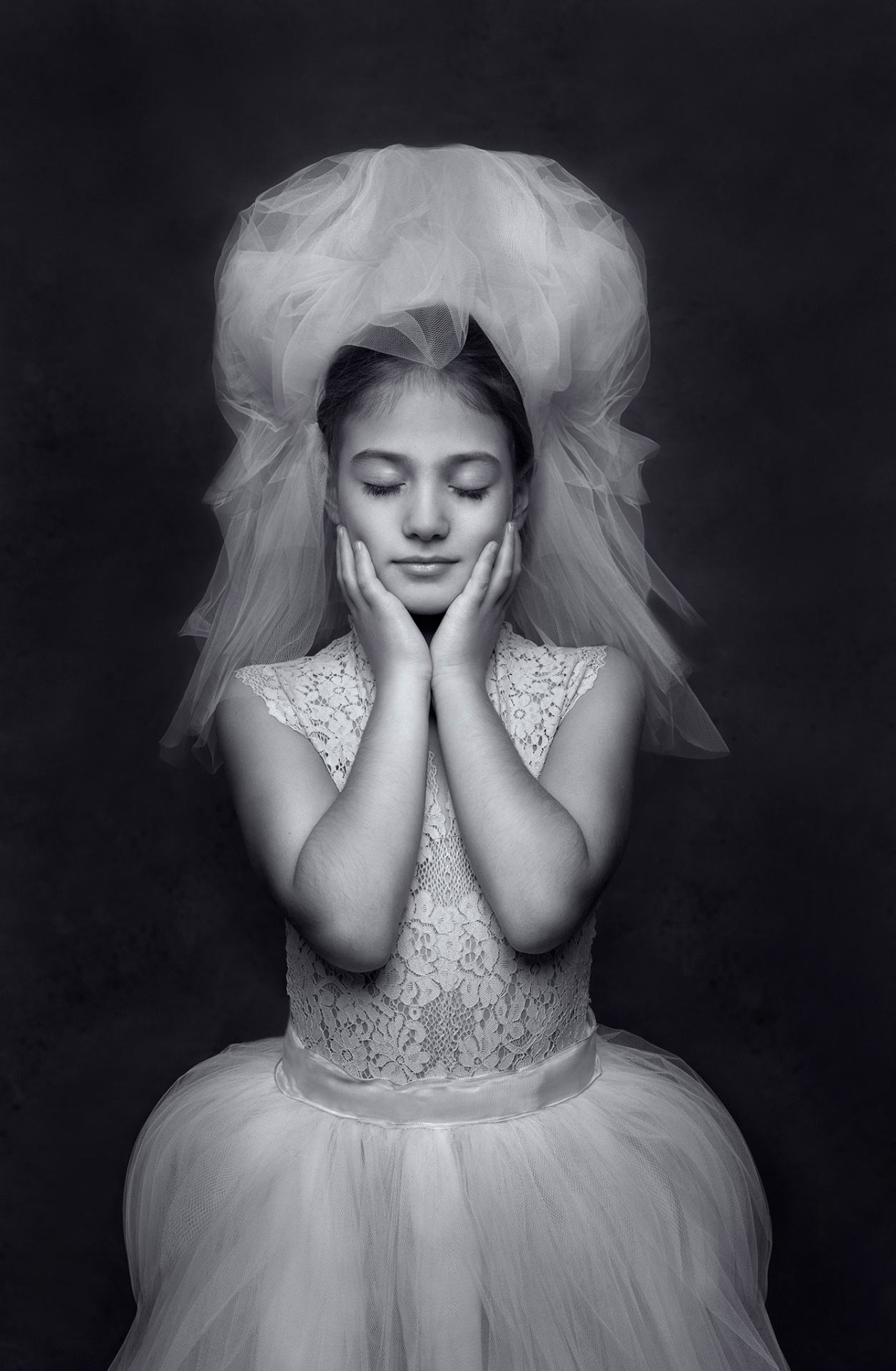 Ritratto in bianco e nero di bambina con abito in tulle e copricapo vaporoso, in posa contemplativa, realizzato da Claudia Spaziani nel suo studio a Bologna.