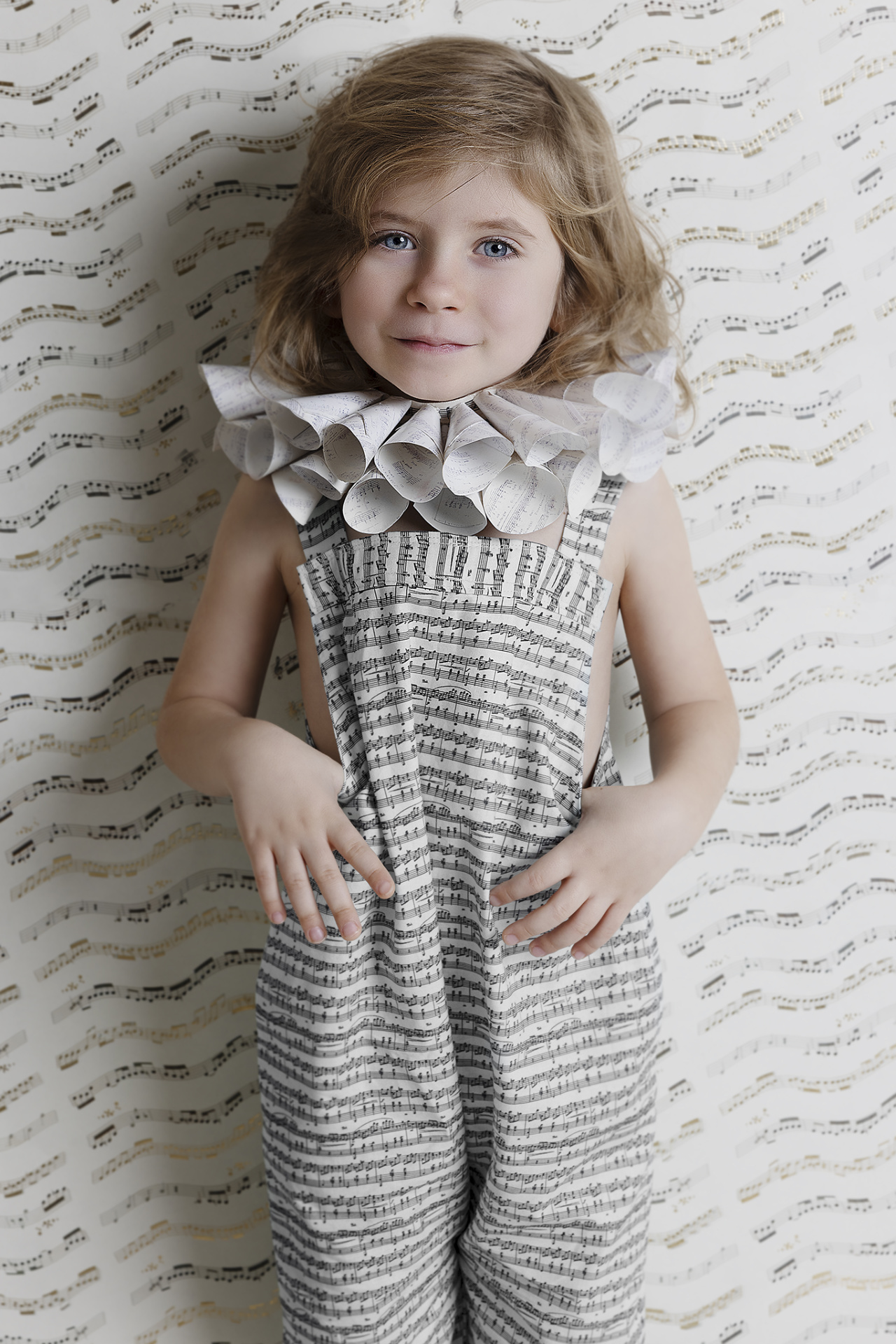 Ritratto creativo di bambino in abito con note musicali e colletto decorativo, su sfondo armonico, scattato da Claudia Spaziani nel suo studio fotografico a Bologna.