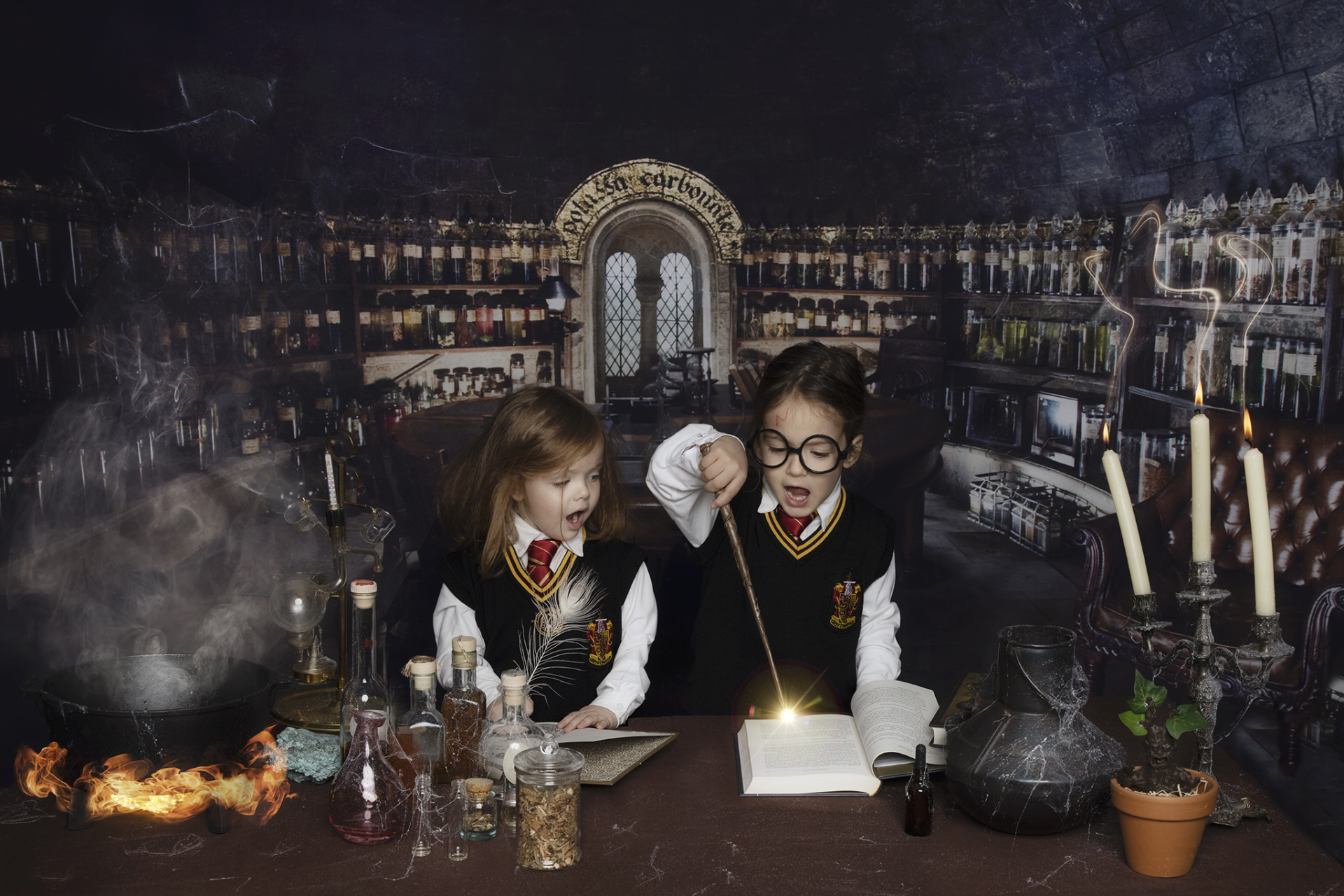 Bambini in costume da Harry Potter e Hermione con candele accese, ambientati in un set da apotecario magico.