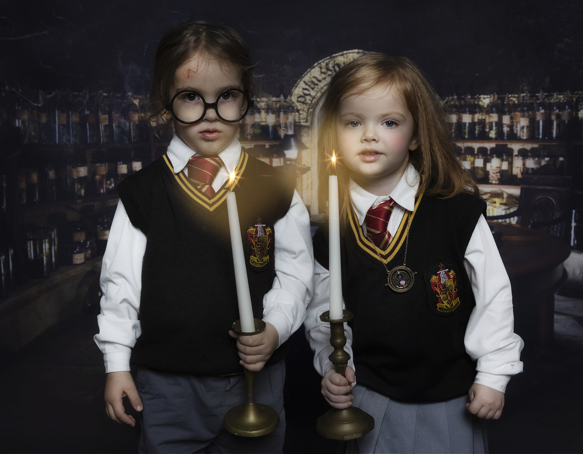 Scena fantasy con bambini in costume da maghi e sfondo con bottiglie, pergamene e piante magiche.