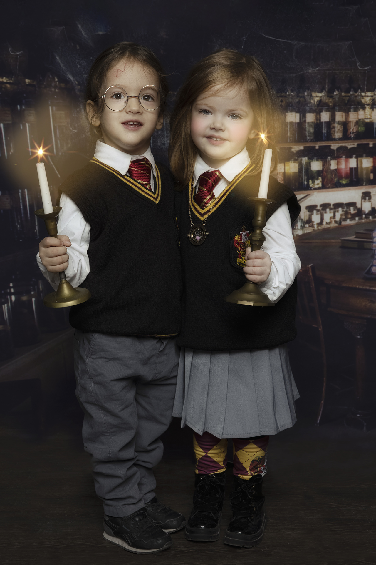 Scena incantata con bambini in aula pozioni, circondati da ampolle, candele e libri antichi.