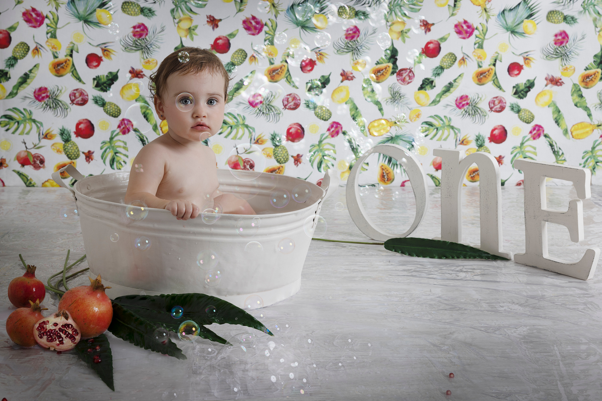 Bambina in costume da leoncino con cappello a criniera, sorridente davanti a blocchi "ONE" e decorazioni verdi. Foto di primo compleanno a tema animale realizzata da Claudia Spaziani nel suo studio fotografico a Bologna.