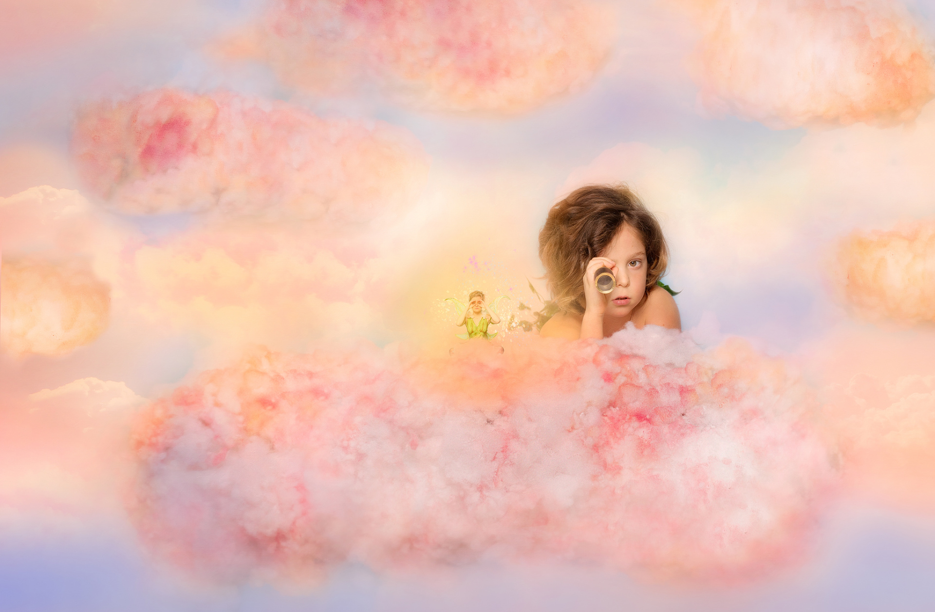 Bambino disteso su nuvola rosa con cannocchiale, accanto a figura fatata con ali. Sfondo onirico con nuvole pastello. Ritratto immaginativo ispirato al mondo di Peter Pan, realizzato da Claudia Spaziani nel suo studio fotografico a Bologna.