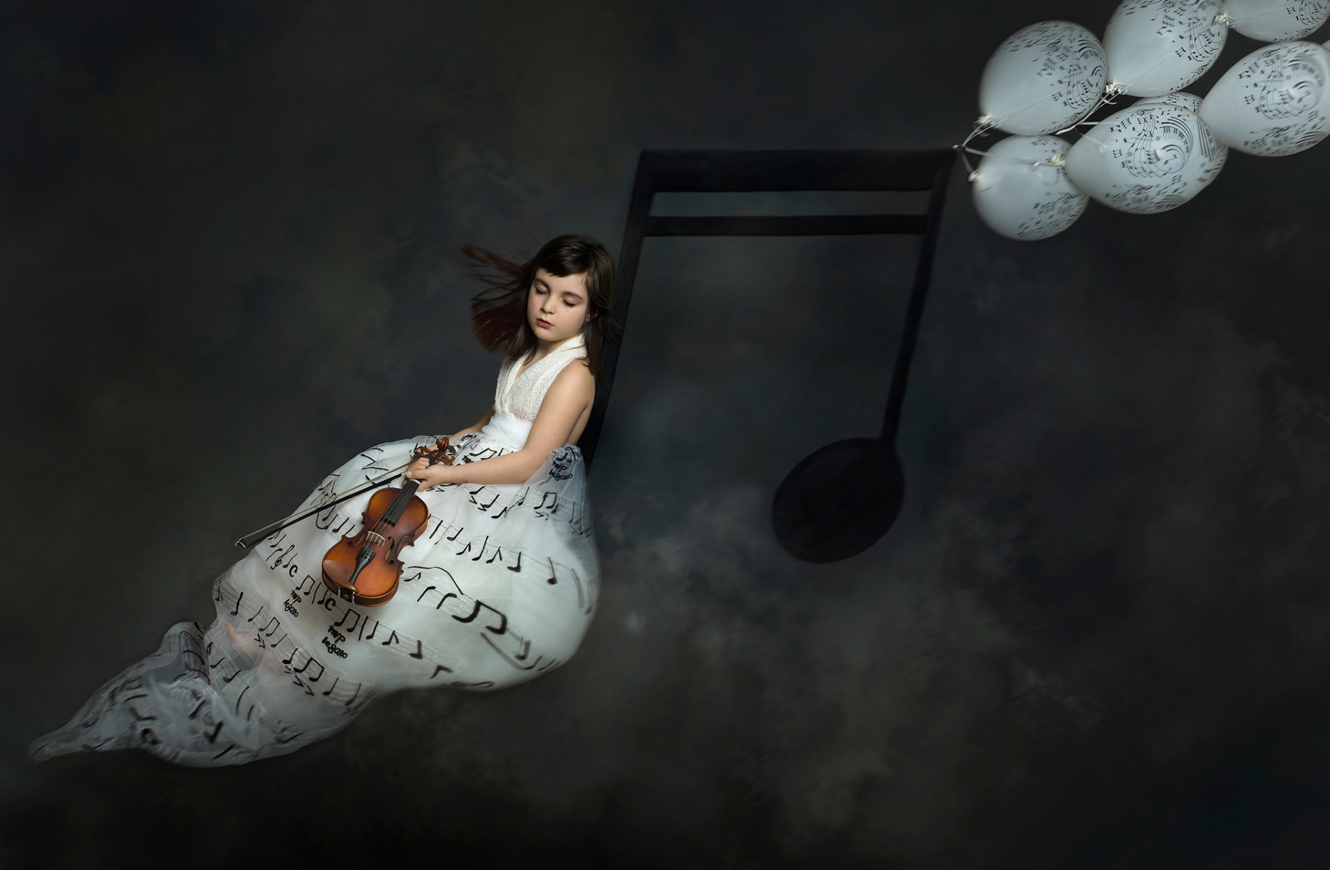 Bambina con abito bianco decorato con note musicali, occhi chiusi mentre suona il violino. Sfondo etereo con palloncini bianchi e nota musicale sospesa. Ritratto artistico e fiabesco realizzato da Claudia Spaziani nel suo studio fotografico a Bologna.