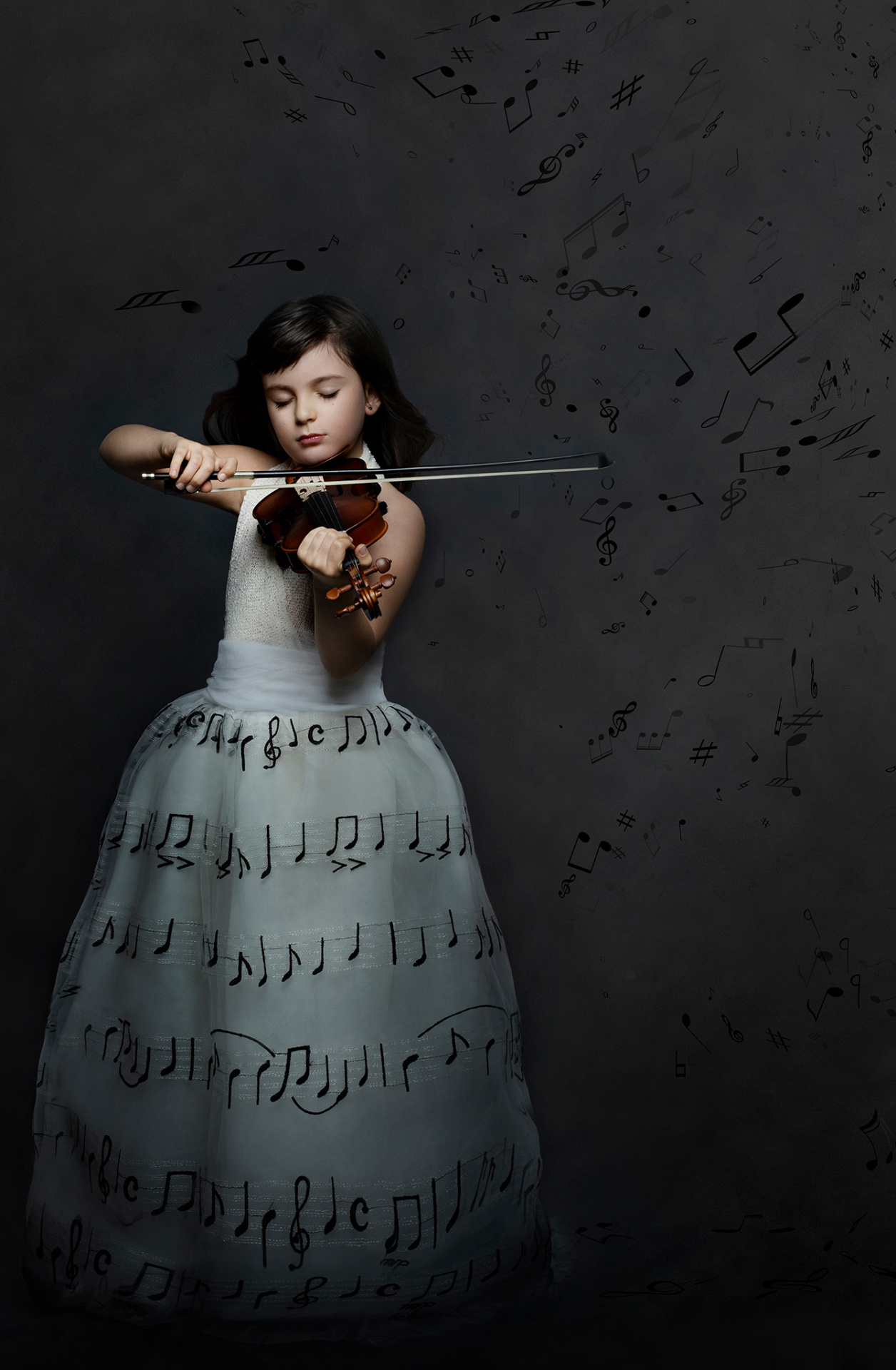 Bambina con abito bianco ricamato con simboli musicali, suona il violino davanti a sfondo scuro con note fluttuanti. Ritratto immersivo e creativo a tema musicale, realizzato da Claudia Spaziani nel suo studio fotografico a Bologna.