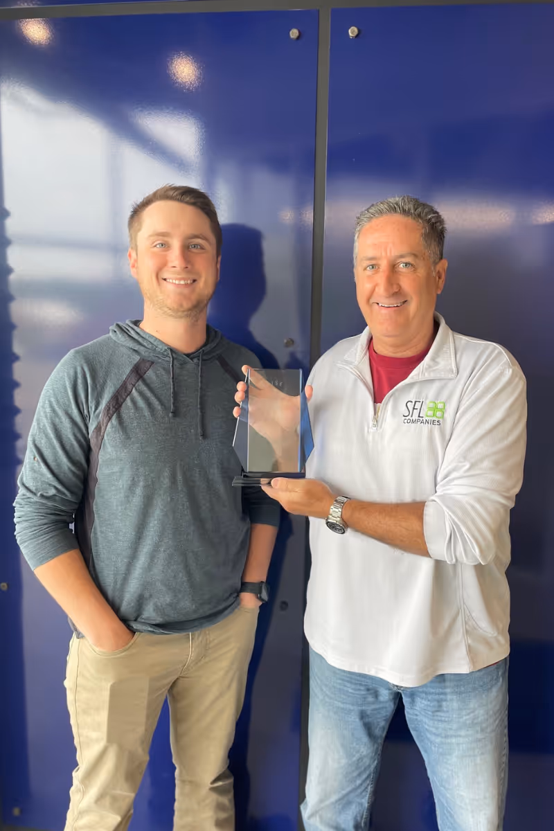 SFL Companies employees celebrating achievement with award in blue office