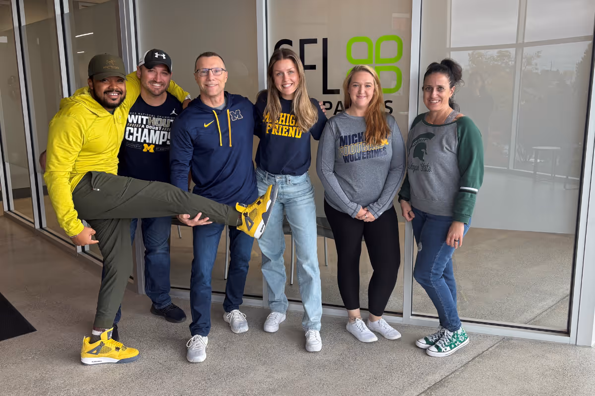 SFL Companies team in Michigan gear poses together in cheerful group photo