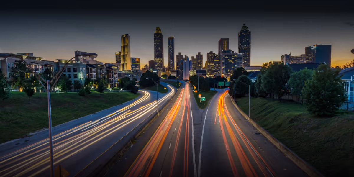 Scene of traffic moving on a highway into a city in the backdrop