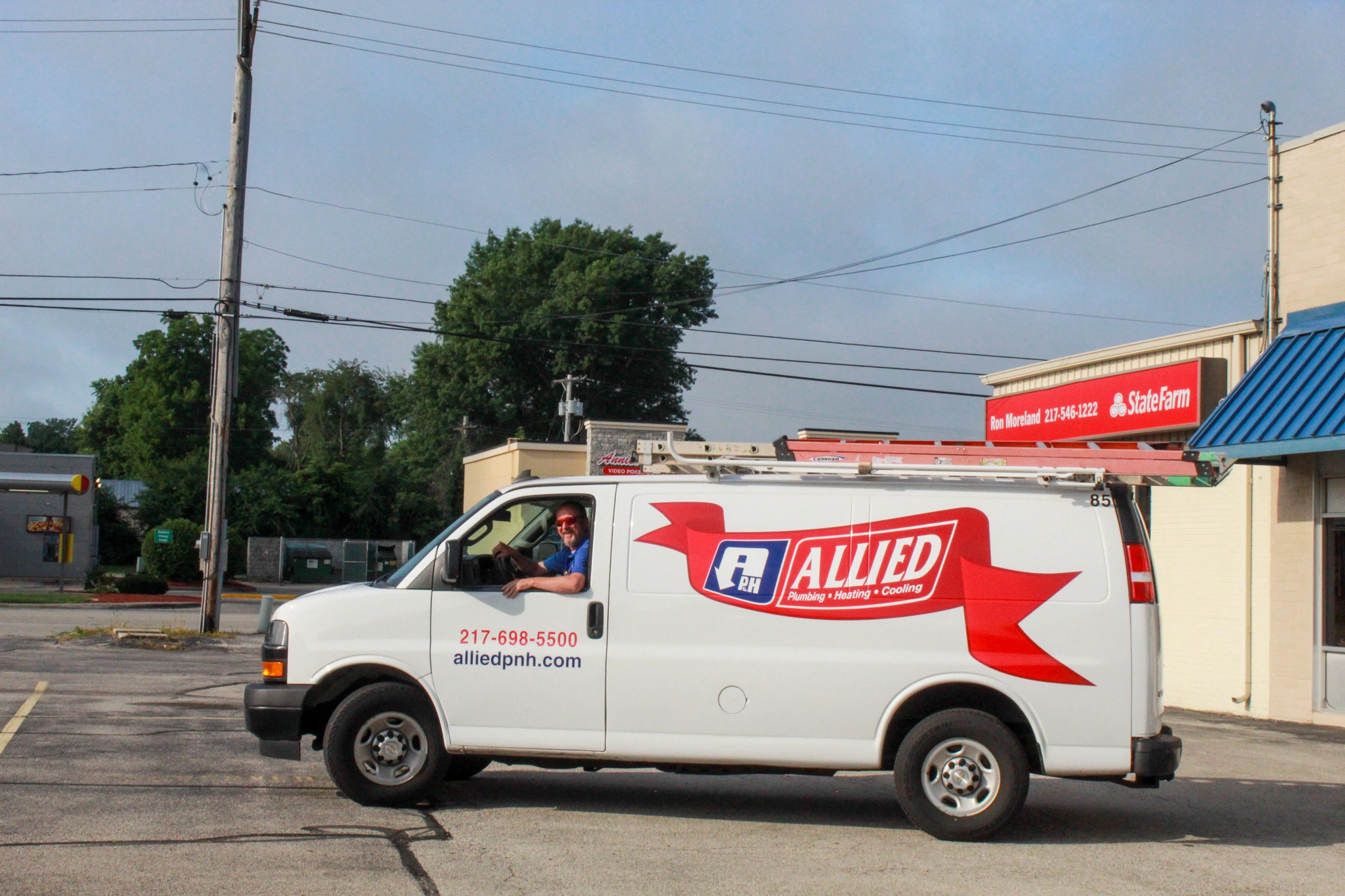 A white service van labeled “Allied Plumbing Heating Cooling” is parked in a lot.