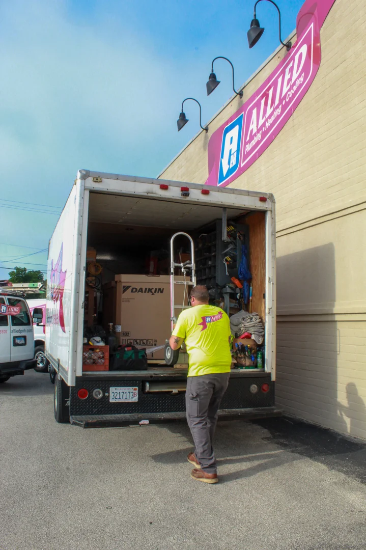 HVAC technician inspecting outdoor AC unit during spring seasonal transition - why spring is the best time for system tune
