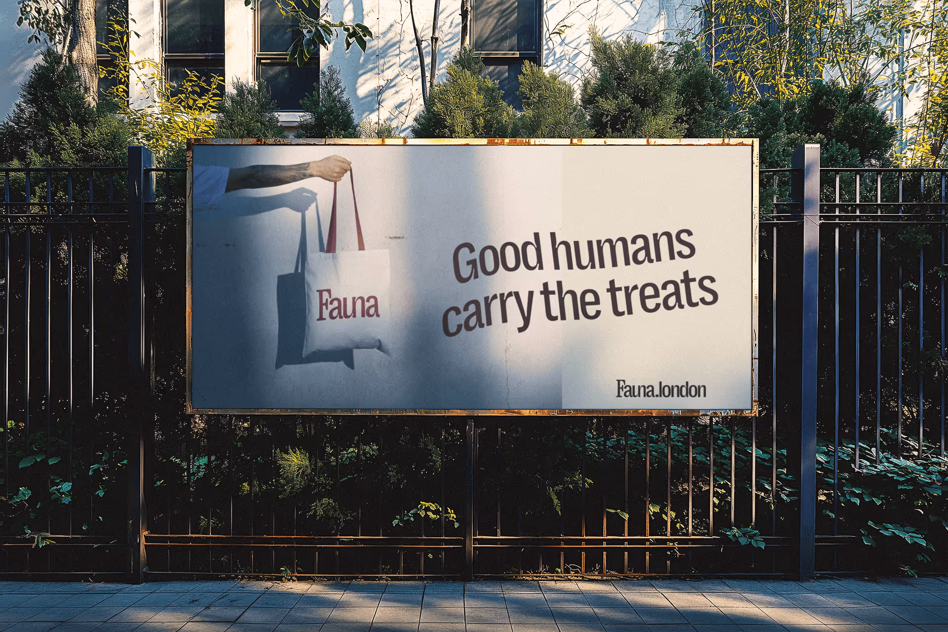 Outdoor billboard with an arm holding a tote bag labeled 'Fauna' and text reading 'Good humans carry the treats' with Fauna.london at the bottom.