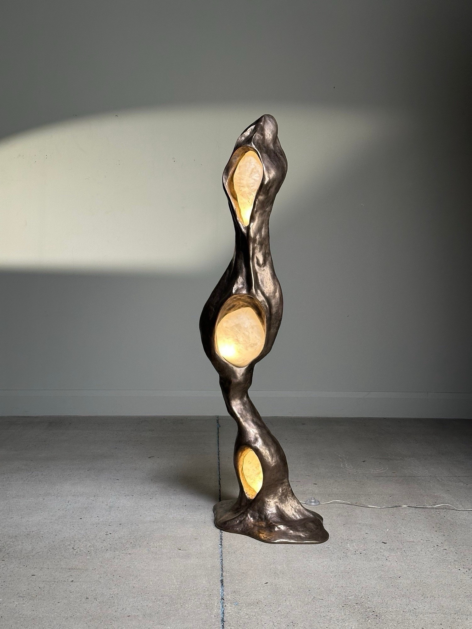 Bronze organic shaped lighting with three yellow spheres emitting light.