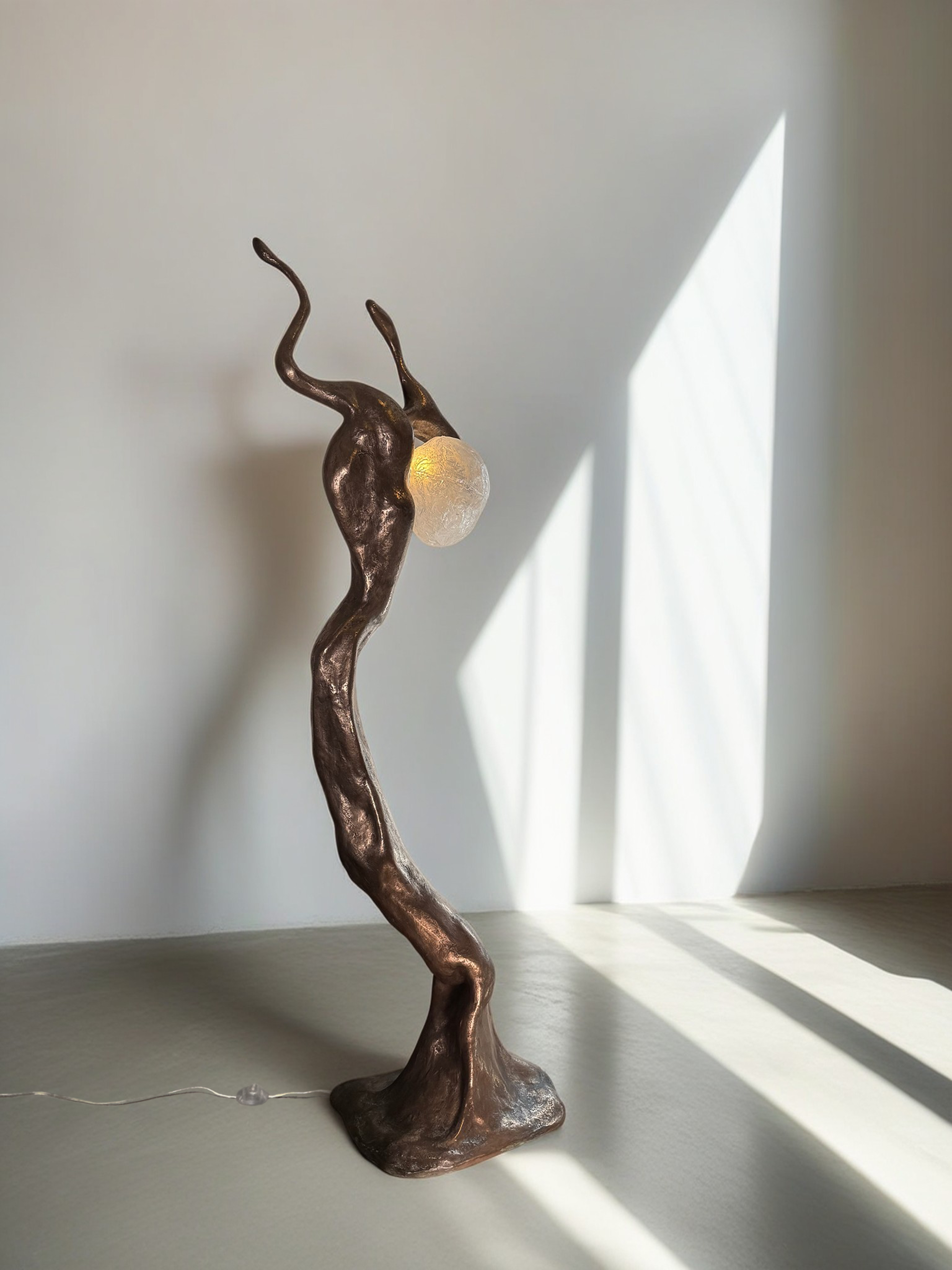 Bronze organic shaped lighting with a yellow sphere emitting light.
