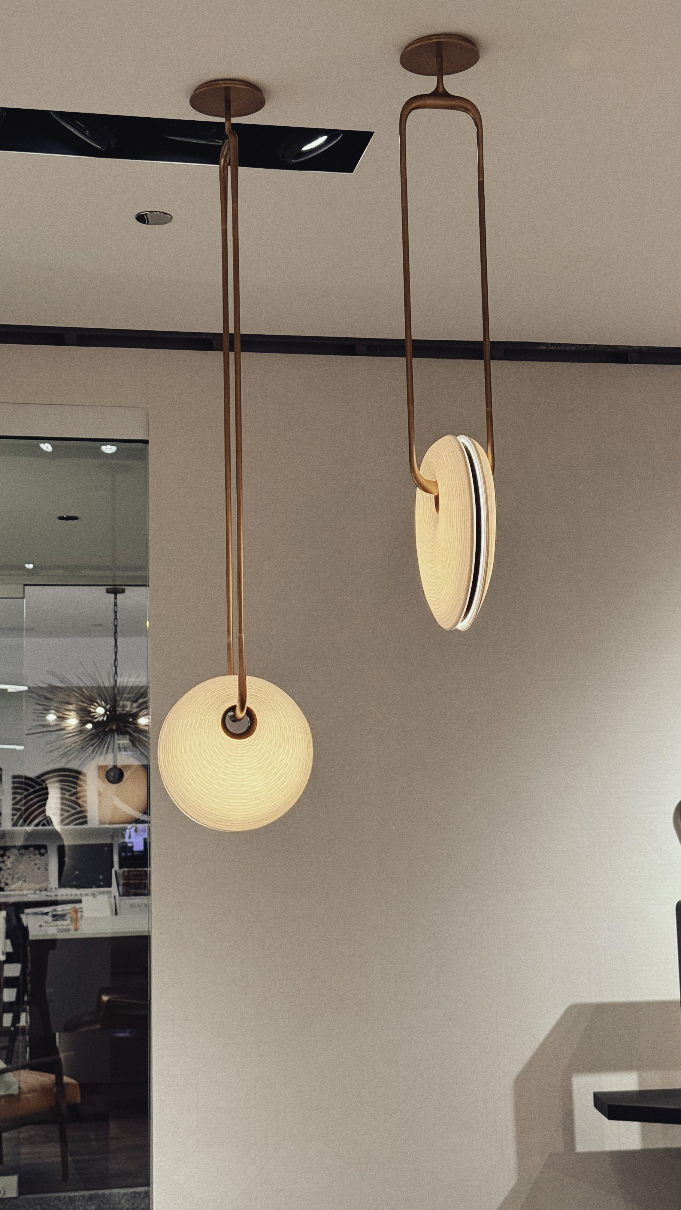 Two textured circular hanging pendant lamps, each hung at a different angle.