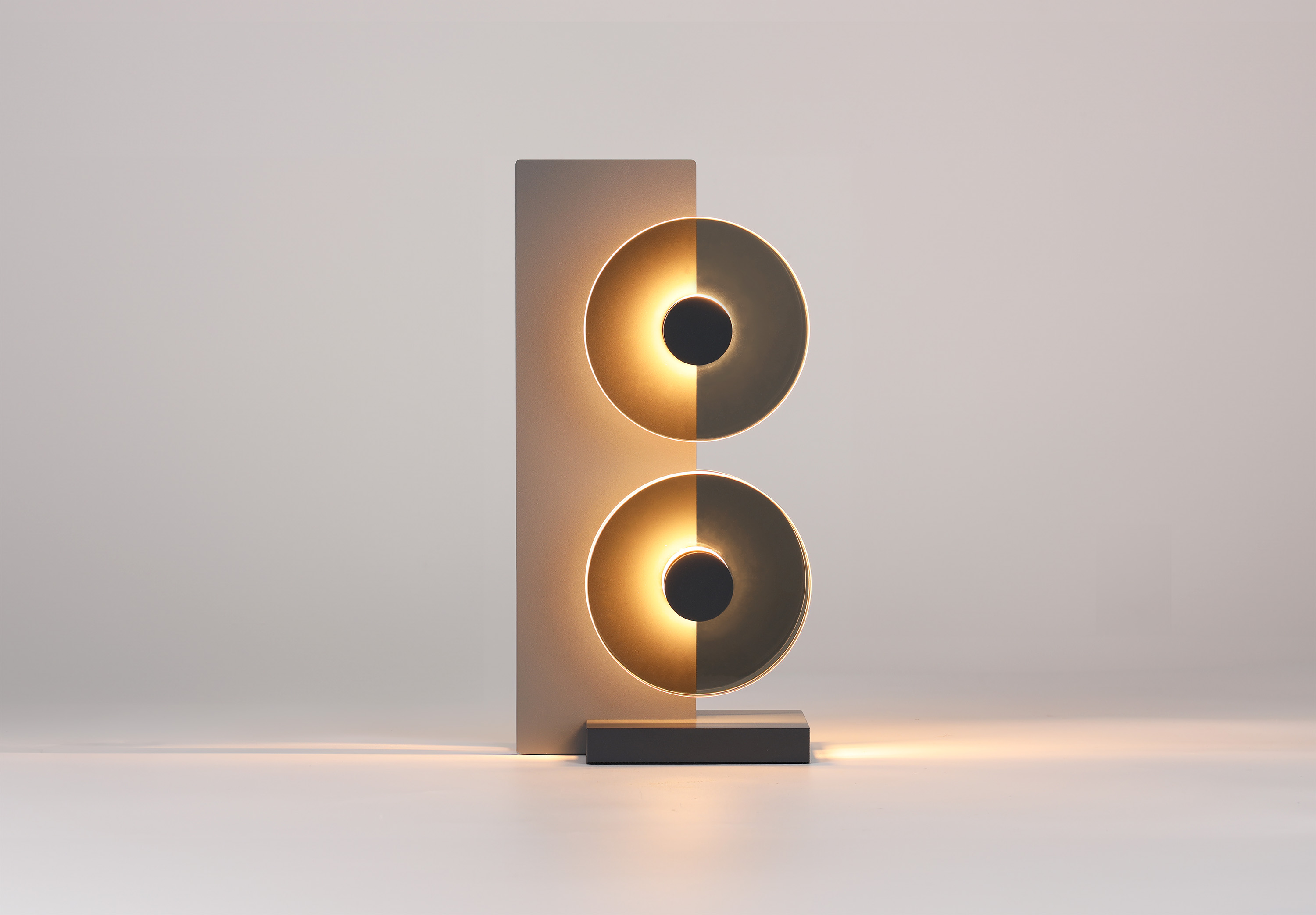 Wood base with two dark gray opaque discs that are illuminated against the wood.