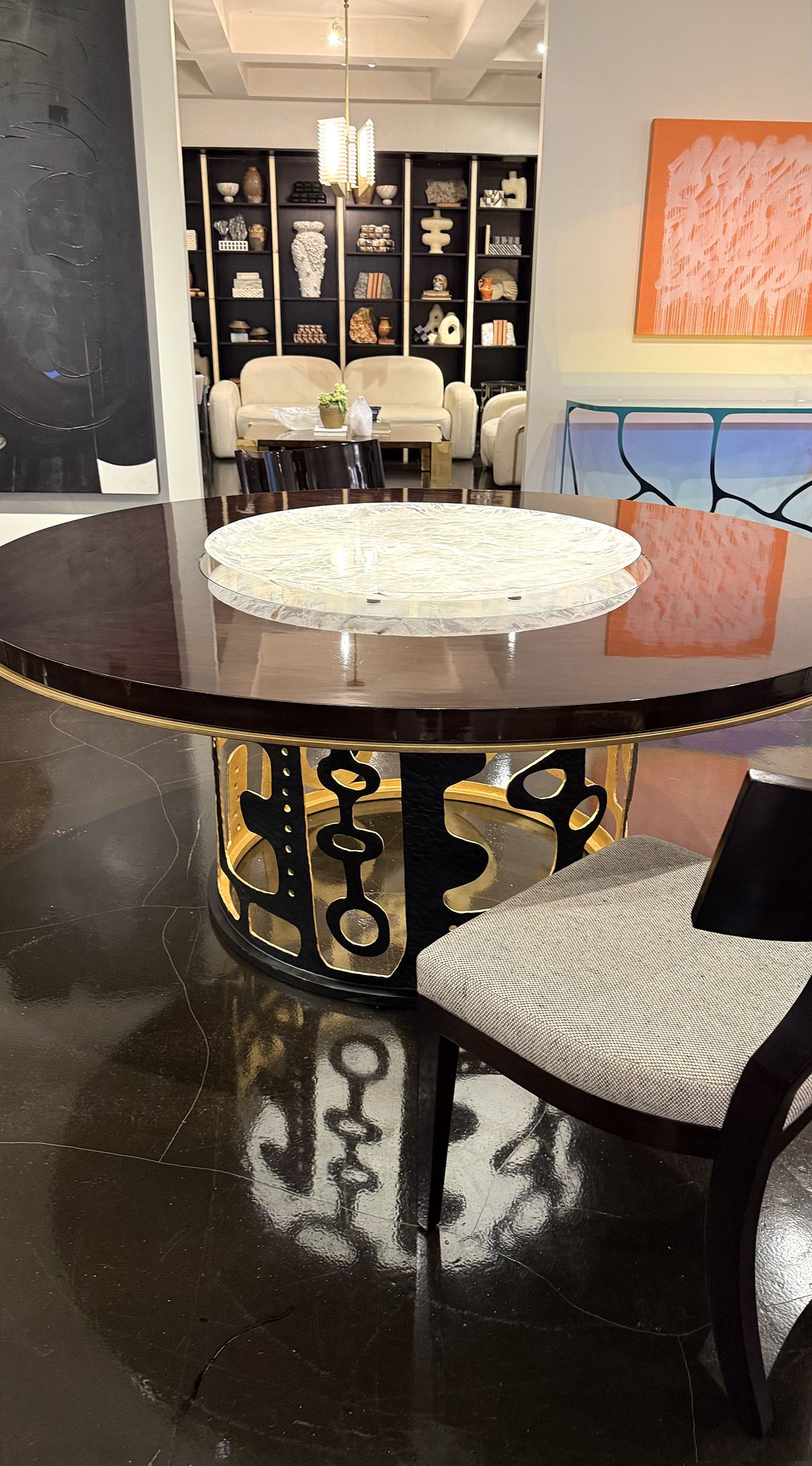 Circular table with a shiny black table top and a metal base with an organic circular pattern cut into it.