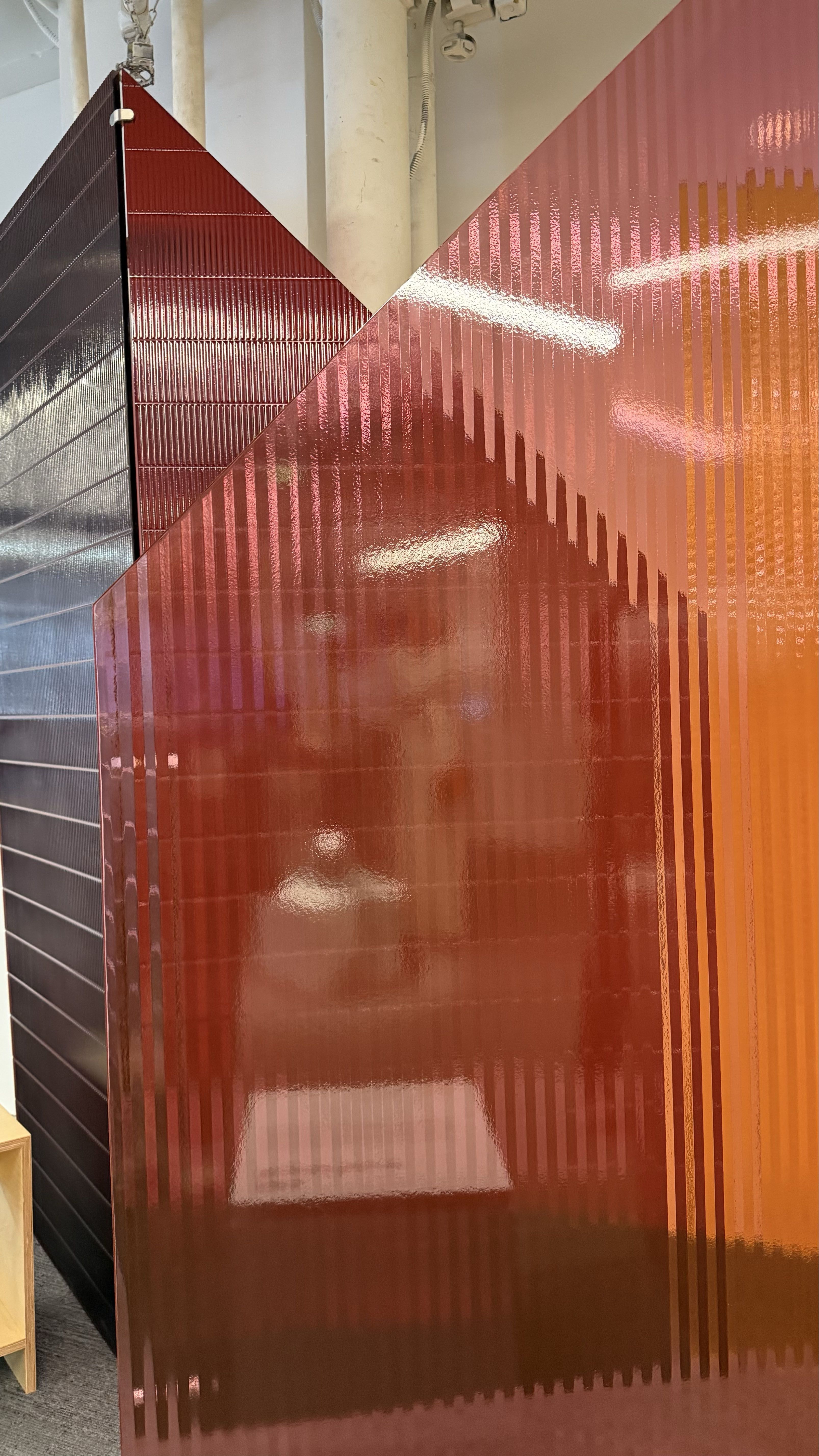 Three plastic opaque walls layered against each other. They are pink, red, and yellow. The 3 layered panels stacked against each other create an array of other colors.
