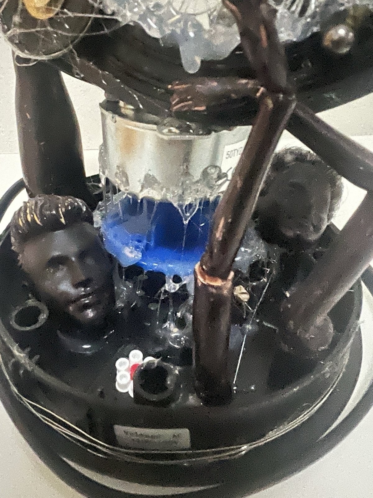 Time: dark assemblage with a sculpted male head, copper pipes, wire and dripping clear resin over blue